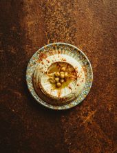 Hummus på en mosaiktallerken, toppet med hele kikærter, olivenolie og paprika.